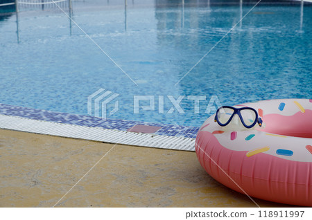A large beautiful brightly colored inflatable swimming lap lies on the edge of a pool filled with clear water. 118911997