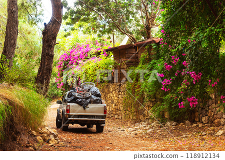 A large truck is parked on a rugged dirt road located in the woods 118912134