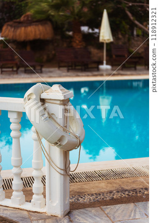 An white life preserver is attached to a railing by a pool 118912321