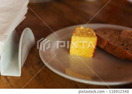 A piece of bread and cupcake on a white plate on a wooden table 118912348