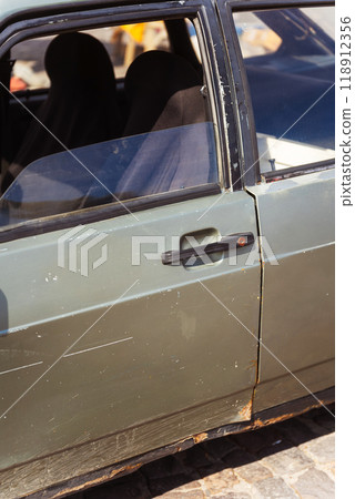 Closeup of a rusty car with a yellow light on its side 118912356