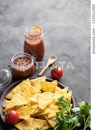 Nachos or tortilla with spicy tomato sauce on a plate with fresh vegetables and herbs  118912400