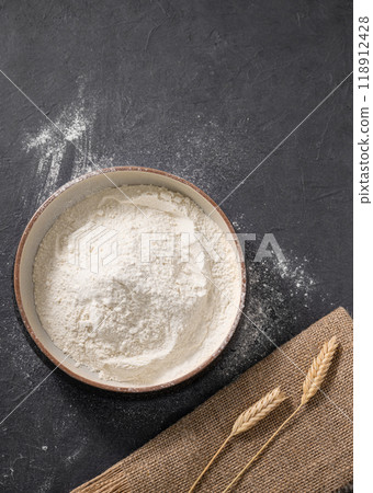 Wheat flour is scattered on a dark background with napkin. Organic baking ingredients.  118912428