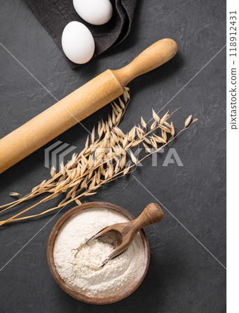 Oatmeal, eggs and rolling pin on a dark background. Organic baking ingredients. Oatmeal, eggs and rolling pin on a dark background. Organic baking ingredients. 118912431