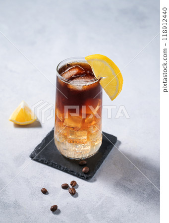 Coffee with tonic in a tall glass with ice and lemon on a light blue background with coffee beans  118912440