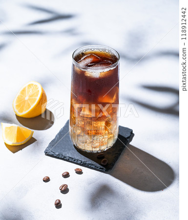 Coffee cold brew with tonic in a tall glass with ice and lemon on a light blue background  118912442
