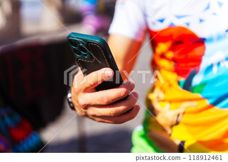A person in a colorful shirt is holding a cell phone A person in a colorful shirt is holding a cell phone 118912461