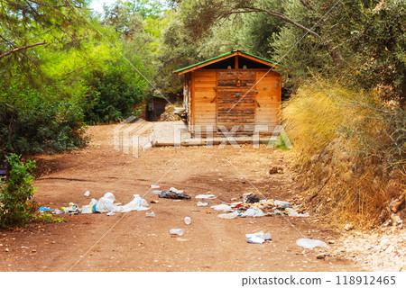large unsightly pile of trash located near small wooden house in forest 118912465