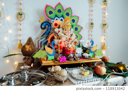Modern Home altar dedicated to God Ganesha with decorations, flowers, traditional offerings, creating a festive atmosphere for Ganesh Chaturthi celebrations. Indian culture, hindu ritual and customs 118913042