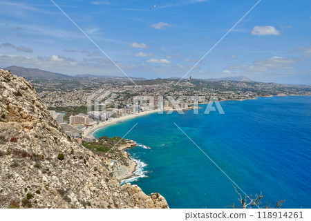 Breathtaking Panoramic View of Calpe's Turquoise Bay from Majestic Cliffside Overlooking Iconic Penon de Ifach Rock Formation. Stunning Costa Blanca Seascape: Calpe's Golden Beaches and Azure Waters Breathtaking Panoramic View of Calpe's Turquoise Bay from Majestic Cliffside Overlooking Iconic Penon de Ifach Rock Formation. Stunning Costa Blanca Seascape: Calpe's Golden Beaches and Azure Waters 118914261