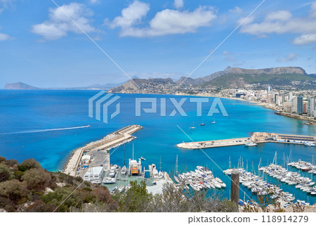 Panoramic Vista of Calpe Spain Coastal Town Yacht Marina Blue Sky Sunny Day Tourism Destination Mediterranean Lifestyle. Aerial View Calpe Spain Costa Blanca Penon de Ifach Rock Mediterranean Sea 118914279