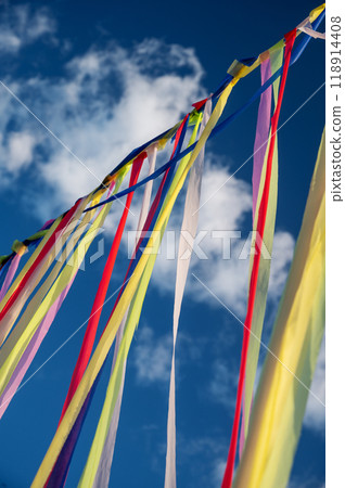 Multicolored ribbons or garlands flutter in the wind on a summer sunny day with a blue sky  118914408