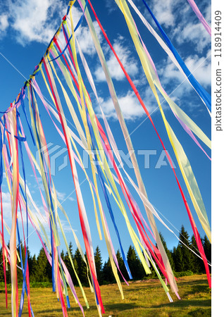 Multicolored ribbons or garlands flutter in the wind on a summer sunny day with a blue sky  118914409