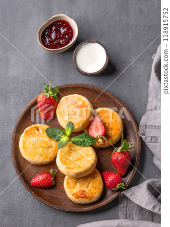Cottage cheese, cheesecakes or syrniki with sour cream, jam, strawberries and mint leaves Cottage cheese, cheesecakes or syrniki with sour cream, jam, strawberries and mint leaves 118915752