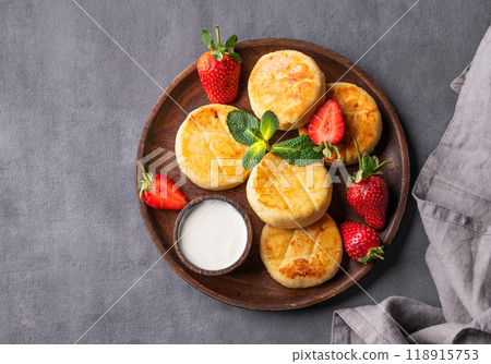 Cottage cheese, cheesecakes or syrniki with sour cream, strawberries and mint leaves Cottage cheese, cheesecakes or syrniki with sour cream, strawberries and mint leaves 118915753