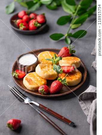 Cottage cheese, cheesecakes or syrniki with sour cream, strawberries and mint leaves Cottage cheese, cheesecakes or syrniki with sour cream, strawberries and mint leaves 118915754