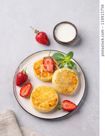 Cottage cheese, cheesecakes or syrniki with strawberries and mint leaves on a white plate Cottage cheese, cheesecakes or syrniki with strawberries and mint leaves on a white plate 118915756