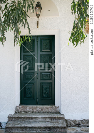 A bright green door in white walls under a canopy of hanging eucalyptus branches. A bright green door in white walls under a canopy of hanging eucalyptus branches. 118915762
