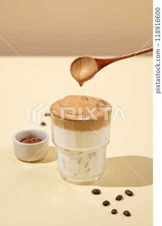 Dalgona coffee. Whipped instant coffee with ice and milk on a yellow background with shadow.  118916600