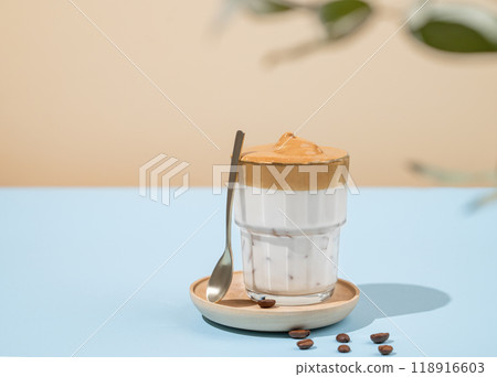 Vegan dalgona coffee. Whipped instant iced coffee with soy milk in a glass on blue background Vegan dalgona coffee. Whipped instant iced coffee with soy milk in a glass on blue background 118916603