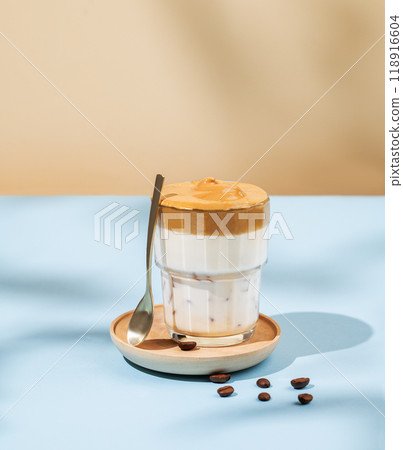 Vegan dalgona coffee. Whipped instant iced coffee with soy milk in a glass on blue background Vegan dalgona coffee. Whipped instant iced coffee with soy milk in a glass on blue background 118916604