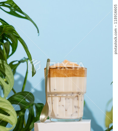 Dalgona coffee. Whipped instant coffee in a glass on a white stand with coffee beans Dalgona coffee. Whipped instant coffee in a glass on a white stand with coffee beans 118916605
