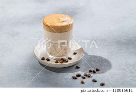 Dalgona coffee. Whipped instant coffee in a glass with coffee beans on a blue background Dalgona coffee. Whipped instant coffee in a glass with coffee beans on a blue background 118916611