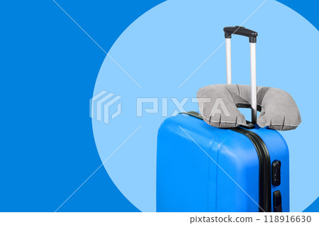 Blue suitcase and travel pillow on a blue background. 118916630