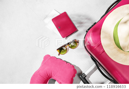 Flat lay pink suitcase with travel accessories, hat and head pillow on a light background. 118916633