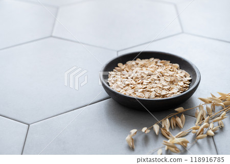 Oatmeal in a wooden plate on a gray concrete tile with dry branch. 118916785
