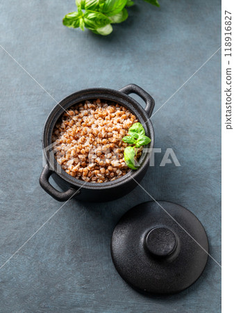 Buckwheat porridge with fresh herbs in a black pan on a dark background. Buckwheat porridge with fresh herbs in a black pan on a dark background. 118916827