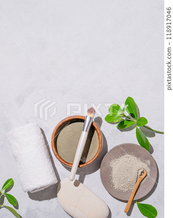 Homemade cosmetics. Organic clay in a bowl with a brush on a light background with shadow and leaves Homemade cosmetics. Organic clay in a bowl with a brush on a light background with shadow and leaves 118917046