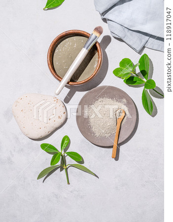 Handmade cosmetics. Organic clay in a bowl with a brush on a light background with shadow and leaves Handmade cosmetics. Organic clay in a bowl with a brush on a light background with shadow and leaves 118917047