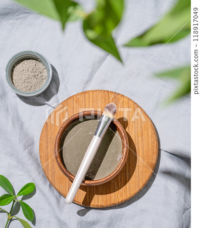 Organic cosmetic blue clay in a bowl with a brush on a wooden board on a linen background 118917049
