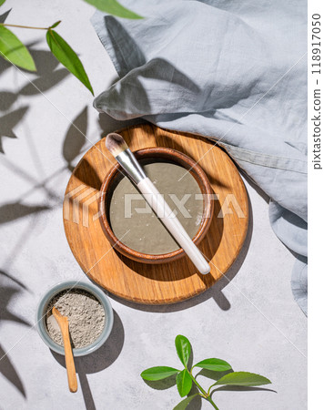 Organic cosmetic blue clay in a bowl with a brush on a wooden board on a light background Organic cosmetic blue clay in a bowl with a brush on a wooden board on a light background 118917050