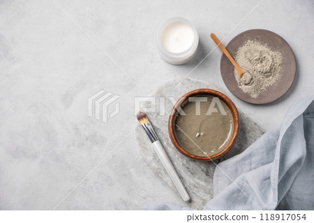 Organic cosmetic with blue clay on a marble board with brush, candle and napkin on light background. Organic cosmetic with blue clay on a marble board with brush, candle and napkin on light background. 118917054