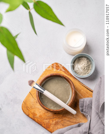 Organic cosmetic with blue clay on a wooden board with brush, candle, branch and napkin Organic cosmetic with blue clay on a wooden board with brush, candle, branch and napkin 118917057