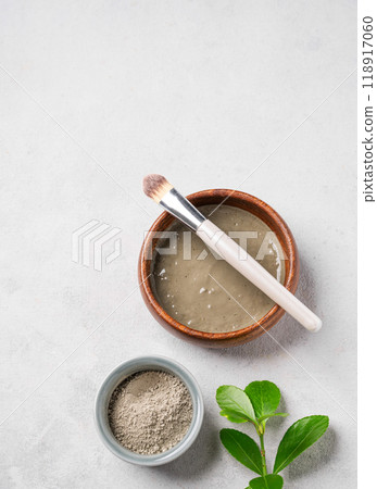 Blue clay with brush on a light background with leaf. Concept for preparing homemade cosmetics. Blue clay with brush on a light background with leaf. Concept for preparing homemade cosmetics. 118917060