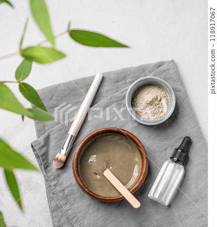 Flat lay of organic cosmetic with blue clay, serum,  brush and branch on a light background. 118917067