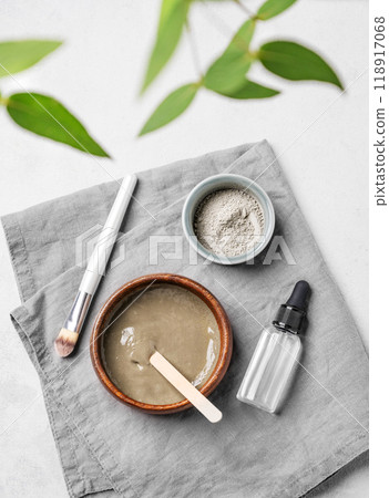 Flat lay of organic cosmetic with blue clay, serum, brush and branch on a light background. Flat lay of organic cosmetic with blue clay, serum, brush and branch on a light background. 118917068