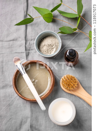 Flat lay of organic cosmetic with blue clay, brush, candle and branch on a linen background. Flat lay of organic cosmetic with blue clay, brush, candle and branch on a linen background. 118917073