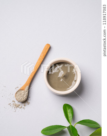 Blue clay in a bowl and spoon on a light background with leaves. 118917083