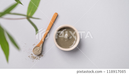 Blue clay in a bowl and spoon on a light background with leaves. 118917085