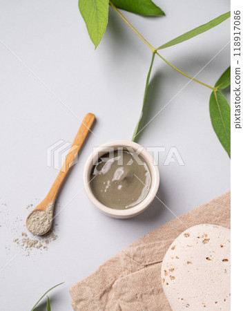 Blue clay in a bowl and spoon on a light background with leaves stone and napkin. Blue clay in a bowl and spoon on a light background with leaves stone and napkin. 118917086
