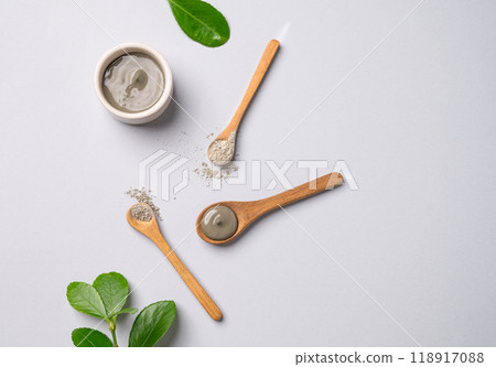 Blue clay in a bowl and spoons on a light background with leaves. Blue clay in a bowl and spoons on a light background with leaves. 118917088
