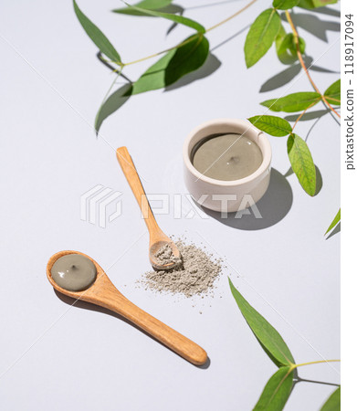 Blue clay in a bowl and spoons on a light background with branch. Blue clay in a bowl and spoons on a light background with branch. 118917094