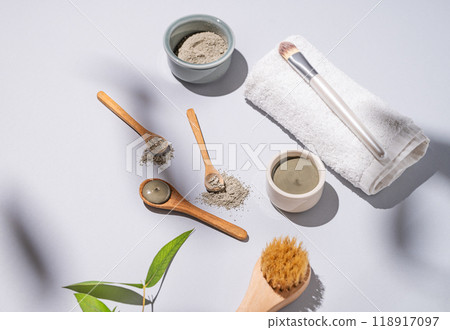 Blue clay in a spoon on a light background with towel, brush and shadows. Blue clay in a spoon on a light background with towel, brush and shadows. 118917097
