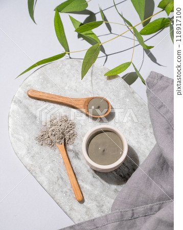 Blue clay in a bowl and spoons on a marble board on a light background with branch and napkin. 118917100