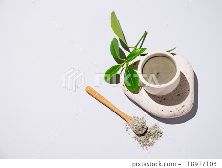 Blue clay in a bowl and spoon on a stone on a light background with leaves. Blue clay in a bowl and spoon on a stone on a light background with leaves. 118917103