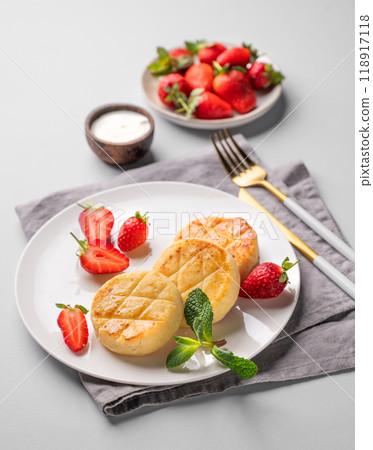 Cottage cheese, cheesecakes or syrniki with strawberries, sour cream and mint leaves Cottage cheese, cheesecakes or syrniki with strawberries, sour cream and mint leaves 118917118